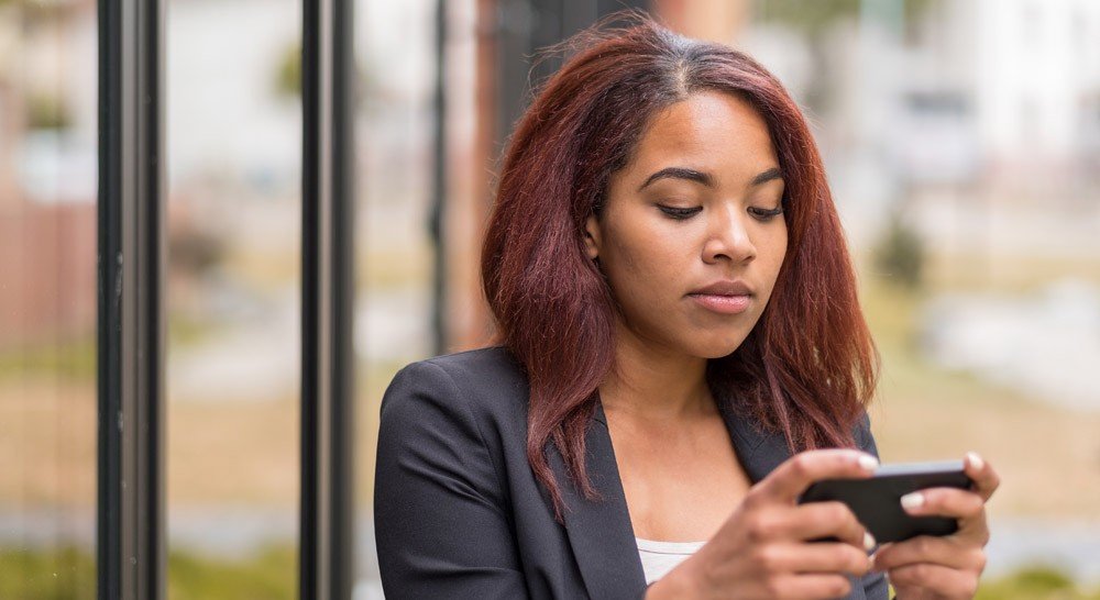 young Black woman plugged into her cell phone
