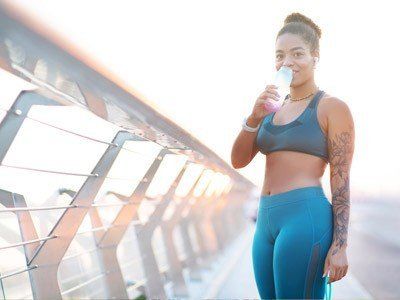 black woman drinking water after exercising